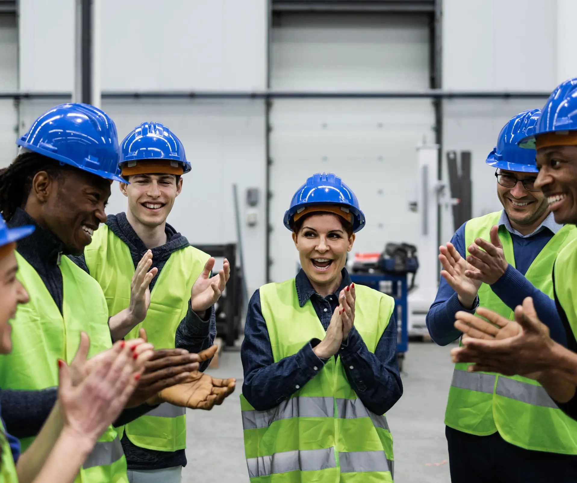 Workers in hard hats clapping and smiling.