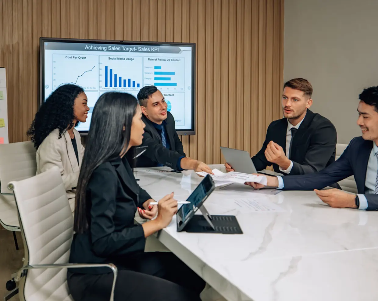 Business meeting with sales presentation screen.